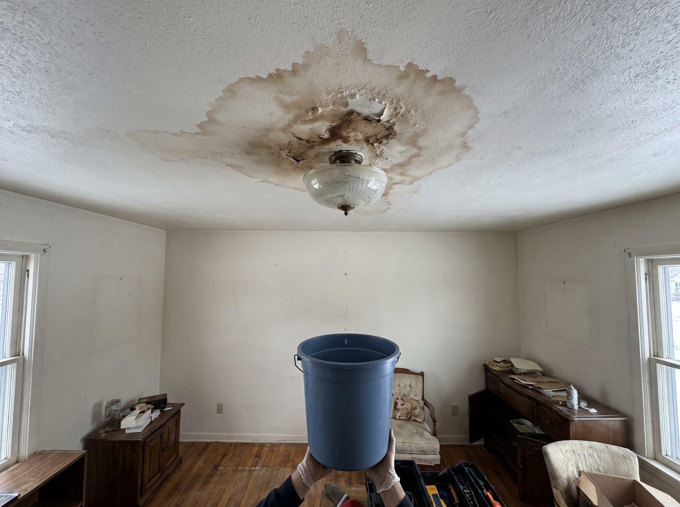 A brown water stain spreading across a ceiling around a light fitting